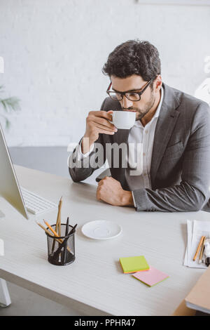 Gut aussehender Geschäftsmann trinken Kaffee im Büro Stockfoto