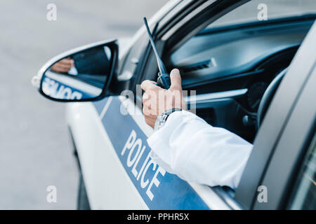 Zugeschnittenes Bild der männlichen Polizisten holding Radio im Auto Stockfoto