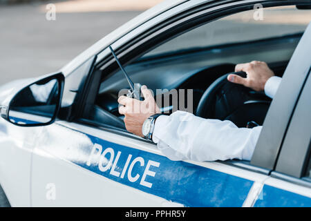 Zugeschnittenes Bild der männlichen Polizisten Holding walkie-talkie im Auto. Stockfoto