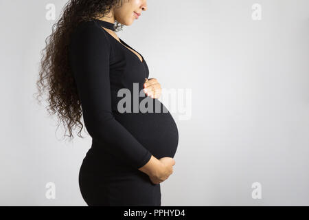 Close-up Studio shoot der schwangeren Frau, ihren Bauch berühren. Auf weissem Hintergrund Stockfoto