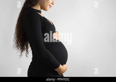 Close-up Studio shoot der schwangeren Frau, ihren Bauch berühren. Auf weissem Hintergrund Stockfoto