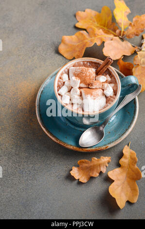 Heiße Schokolade mit Marshmallows und Herbstlaub auf Stein oder Beton Hintergrund Stockfoto