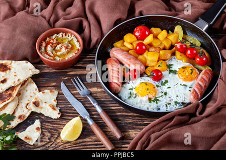 Frühstück Mahlzeit: Ahorn verglaste butternut squash, Spiegeleier Eier, gewürzt mit frischer Petersilie, gebratene Würstchen, in einer Pfanne, mit Baba serviert. Stockfoto