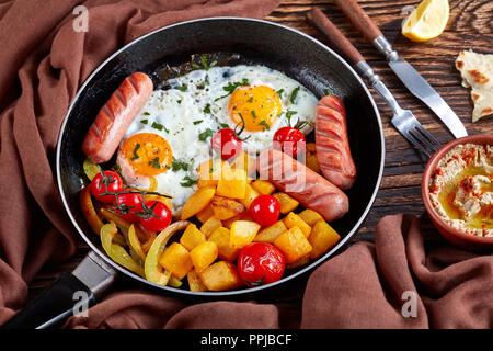 Gesundes Frühstück: Ahorn verglaste Kürbis, Spiegeleier mit frischer Petersilie, gebratene Würstchen, in einer Pfanne mit cremiger Baba ganoush Sauce, Pita, Zitrone Stockfoto