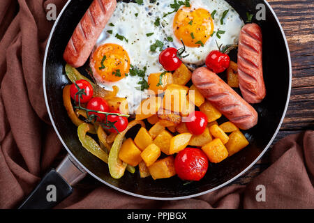 Ansicht von oben auf eine Pfanne mit fallen Frühstück: Ahorn verglaste Kürbis, Spiegeleier, gebratene Wurst und Tomaten, gewürzt mit frischer Petersilie Stockfoto