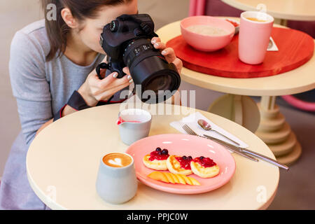 Junge Frau essen Fotograf blogger schießt das Frühstück im Cafe, Verarbeitung Stockfoto