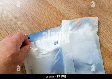 Person reißt die Eröffnung einer Zeitschrift Wrap aus biologisch abbaubarem Kunststoff Maisstärke, Großbritannien Stockfoto