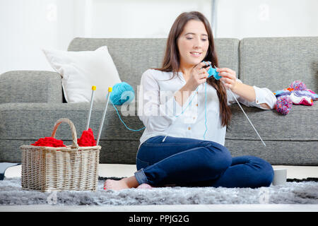 Junges Mädchen saß auf dem Boden stricken Stockfoto