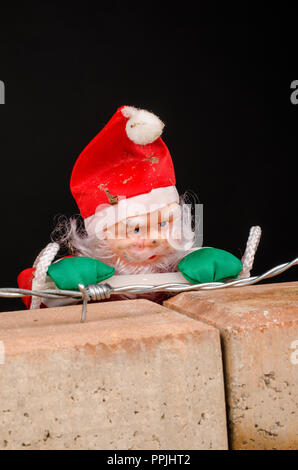 Santa Versuch, die Wand ein zuwanderungskonzept zu klettern Stockfoto