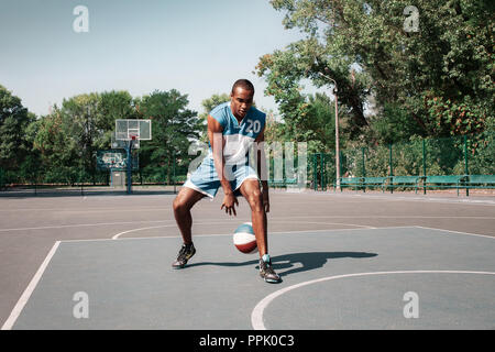 Bild von jungen verwirrt afrikanischen Basketball Spieler üben im Freien. Passen afro Mann in der Bewegung und Bewegung. athletischen und Sport Lifestyle Konzept Stockfoto