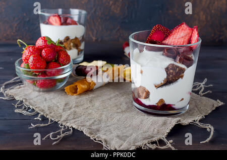 Schokolade Cookies, Sahne und Erdbeeren Nachtisch in einem Glas auf einem dunklen Hintergrund, leckere Kleinigkeit, Kopie Raum Stockfoto