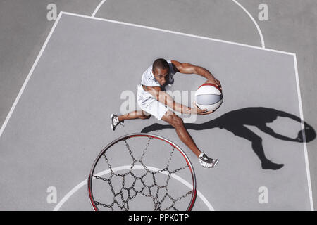 Bild von jungen verwirrt afrikanischen Basketball Spieler üben im Freien. Passen afro Mann in der Bewegung und Bewegung. athletischen und Sport Lifestyle Konzept. Ansicht von oben Stockfoto