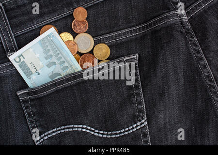 Euro-banknoten und -münzen in schwarzen Jeans Gesäßtasche Stockfoto