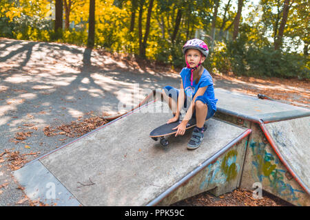 Ein junges Mädchen ist ein ranpe sitzen auf dem Longboard Stockfoto