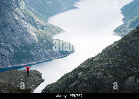 Ringedalsvatnet See. Mädchen im roten Mantel auf Rock schaut auf die Berge in der Nähe von trolltunga Stockfoto