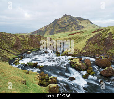 Schönen Kaskaden auf dem Fluss Skoga, Island. Schlucht über dem Wasserfall Skogafoss. Erstaunlich in der Natur. Grünes Gras und Moos. Blick auf die Berge top Stockfoto