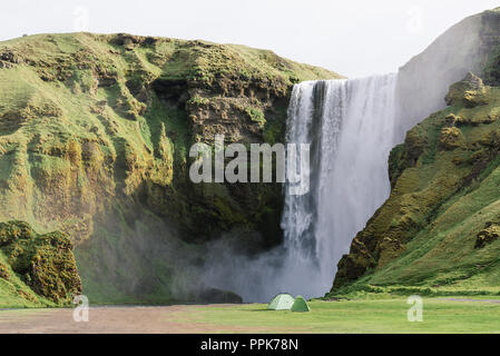 Der schöne Wasserfall Skogafoss im Süden Islands. Das Wahrzeichen der Stadt. Sommer Landschaft an einem sonnigen Tag. Camping Zelte Stockfoto