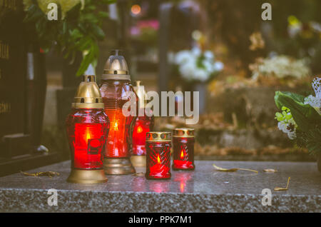 Bunte brennende Kerzen während der Allerheiligen auf dem Friedhof in herbstlicher Atmosphäre Stockfoto