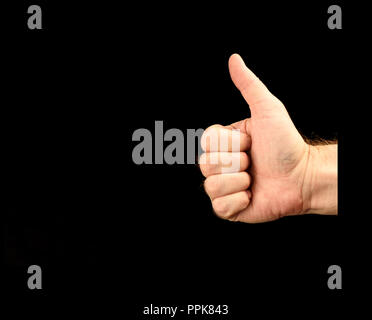 Des Menschen Hand, Daumen hoch auf schwarzem Hintergrund Stockfoto