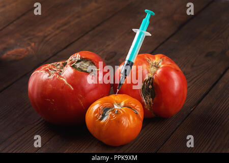 Verwöhnt, Faul drei Tomaten mit Spritze auf einem dunklen Hintergrund. Stockfoto