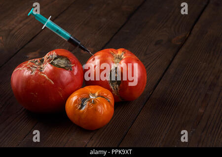 Verwöhnt, Faul drei Tomaten mit Spritze auf einem dunklen Hintergrund. Stockfoto