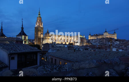 Die Kathedrale von Toledo, Spanien in der Dämmerung, der Alcazar auf der rechten Seite. Primas Kathedrale der Heiligen Maria von Toledo wurde 1226 begonnen. Stockfoto