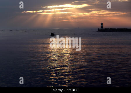 Herbst Sonnenuntergang an der Mündung des Flusses Douro, Porto, Portugal, sehen die neuen Leuchtturm und Mole und einem kleinen Fischerboot in Mühe Stockfoto