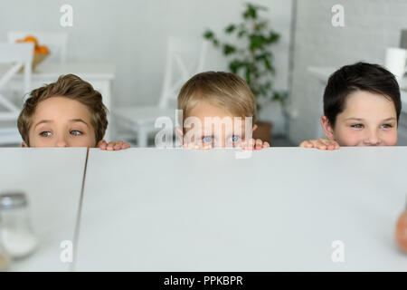 Verdeckt Blick auf kleine Jungen versteckt sich hinter einem Tisch und an der Kamera zu Hause suchen Stockfoto