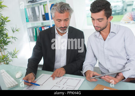 Zwei Architekten diskutieren auf Blueprints in einem Büro Stockfoto