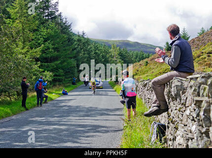 Stufe 5 Tour durch Großbritannien 2018. Zuschauer sitzen auf dem trockenen Steinmauer begrüßt Ankunft von Michelton Scott im Mannschaftszeitfahren, Whinlatter Pass, Cumbria. Stockfoto