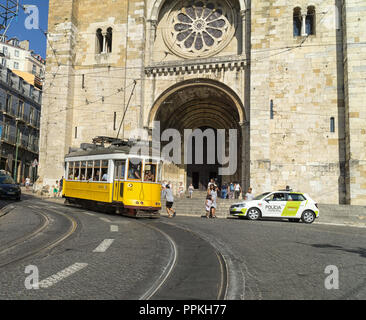 Lissabon, Portugal - 31. August 2018: gelbe Tram Linie 28 vor dem Se Kathedrale; Eine nicht identifizierte Junge springt auf eine Straßenbahn. Stockfoto