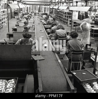 1950er Jahre, historische, Frauen auf einer Produktionslinie in einer Fabrik der Britischen immer bereit, elektrische Firma (GEREK) einer der führenden britischen Hersteller von Batterien, Taschenlampen, Fahrradbeleuchtung und Radios in dieser Ära. Mit einer Reihe von Fabriken um Großbritannien und Tausende von Arbeitern, die stets bereit ist, dominiert die Zink-Kohle-Batterie Markt sowohl in Großbritannien als auch in Südafrika. Stockfoto