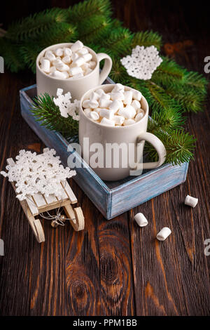 Zwei Tassen heißer Schokolade und Marshmallows und gestrickte Schneeflocken auf einem dunklen Hintergrund Stockfoto