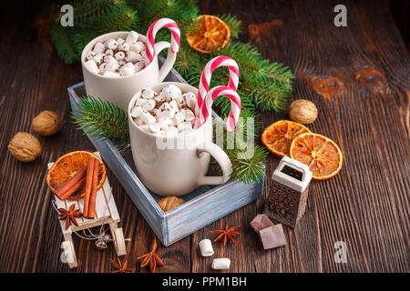 Zwei Tassen heißer Schokolade mit Marshmallows und Zuckerstangen auf einem dunklen Hintergrund Stockfoto