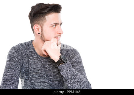 Junge legerer Mann nachdenklich auf den Boden stellen, während auf seine rechte Seite suchen, vor weißem Hintergrund Stockfoto