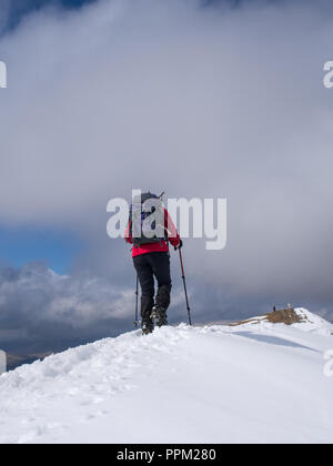 Eine weibliche Wanderer nähert sich dem Gipfel des Ben Vorlich, in der Nähe von Loch verdienen, an einem klaren Wintertag in Schottland Stockfoto