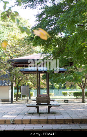 Holz- kleine Sitzbank mit Dach in ruhigen Asiatischen Park im Spätsommer Stockfoto