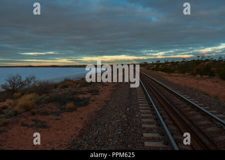 Central Australian Railway führt am Ufer des Salzsees Gairdner entlang. Bei Sonnenuntergang. Australien Stockfoto