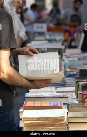 Lissabon, Portugal, September 01, 2018: Rua Anchieta Wochenende Buchmarkt Stadtteil Chiado; unbekannter Mann mit einem grauen Bart ist gerade ein Buch. Stockfoto