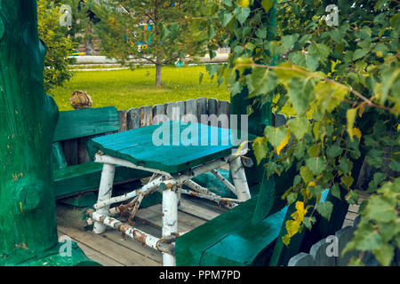 Eine Tabelle der Birke Baumstämme mit schwarzen Streifen und grünen Mainboards mit zwei Bänken Stockfoto