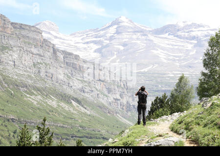 Eine Frau am Monte Perdido massiv starrte, umgeben von hohen Bergen, Pinien und Tannen wald und einen blauen Himmel mit einigen Wolken im Ordesa, Spanien. Stockfoto