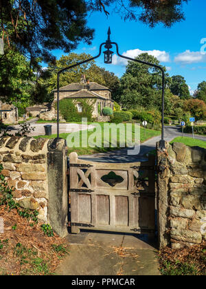 Auf der Suche durch das Tor bei St. Oswalds Kirche zu den alten armenhäuser an leathley North Yorkshire England Stockfoto