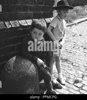 1960, historische, zwei Jungen in einem gepflasterten Straße ein Spiel der Cowboys und Indianer, England, UK. Stockfoto