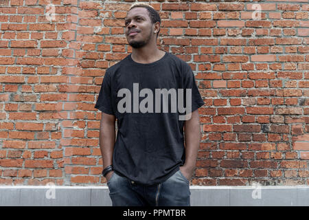 Der dunkelhäutige Mann in Schwarz leer T-Shirt auf gemauertem Hintergrund. Stockfoto