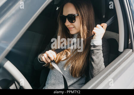 Das Mädchen ist das Anlegen des Sicherheitsgurts im Auto vor der Reise. Stockfoto