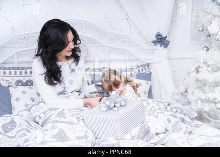 Mutter und Tochter morgens im Bett mit Geschenken am Vorabend von Weihnachten Stockfoto