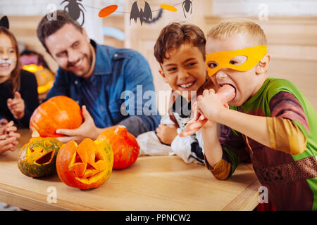 Blonde junge tragen Ninja Turtle Kostüm spielen Tricks Essen hand Cookie Stockfoto