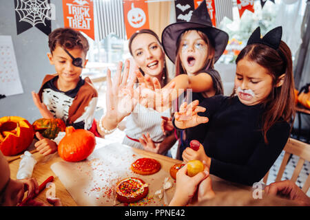 Mutter und Kinder mit bemalten Gesichtern Vorbereitung feier Tabelle für Halloween Stockfoto