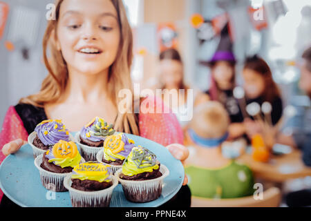 Schöne blonde Mädchen Gefühl glücklich halten Platte mit Feier Cupcakes Stockfoto