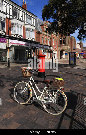 Eine weiße Damen Fahrrad gesichert ist mit einem Stand auf dem breiten Bürgersteig von Lord Street in Southport, die starke Herbst Sonne schafft lange Schatten. Stockfoto